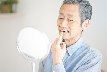 鏡で歯を確認する男性